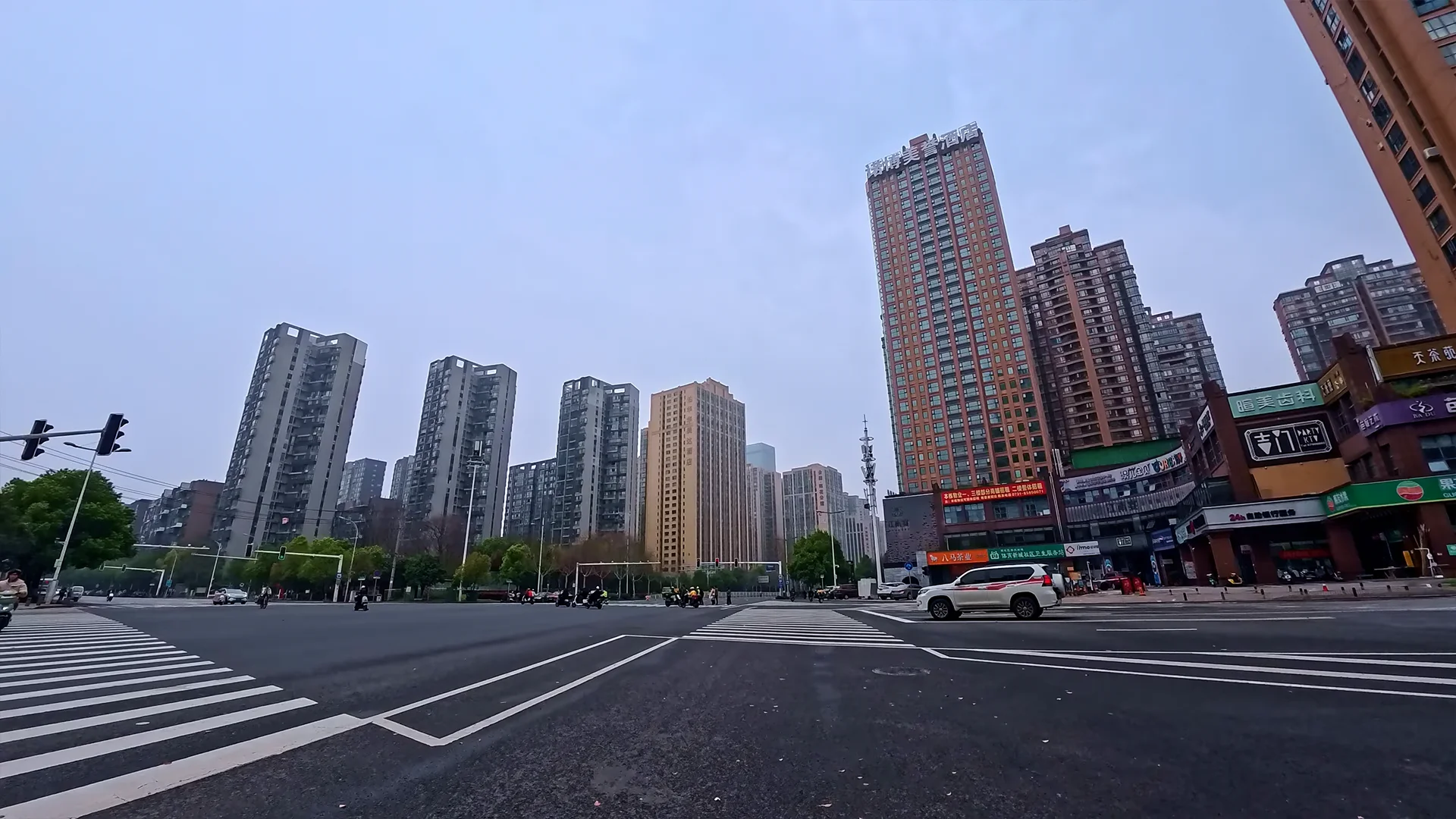 Changsha downtown intersection with modern high-rise buildings, overcast sky and steady urban traffic flow in a 4K scooter POV ride