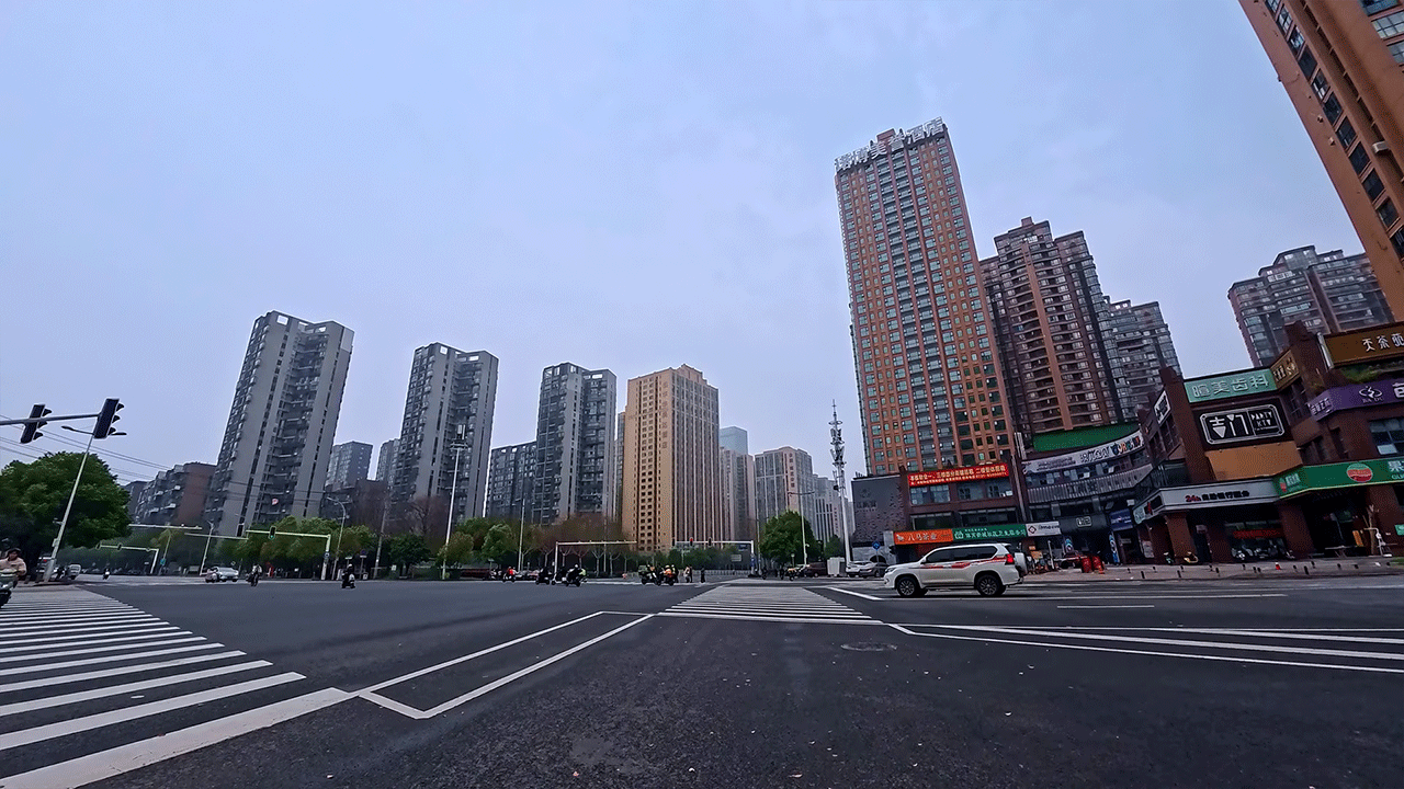 Changsha city intersection with high-rise buildings under an overcast sky during an electric scooter ride