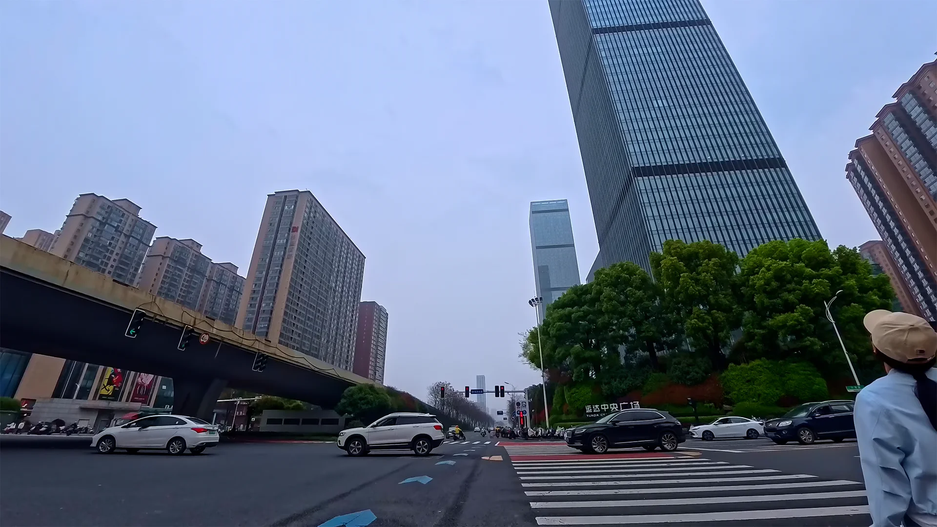 Changsha wide intersection with steady urban traffic flow under an overcast sky, captured during a 4K electric scooter POV ride