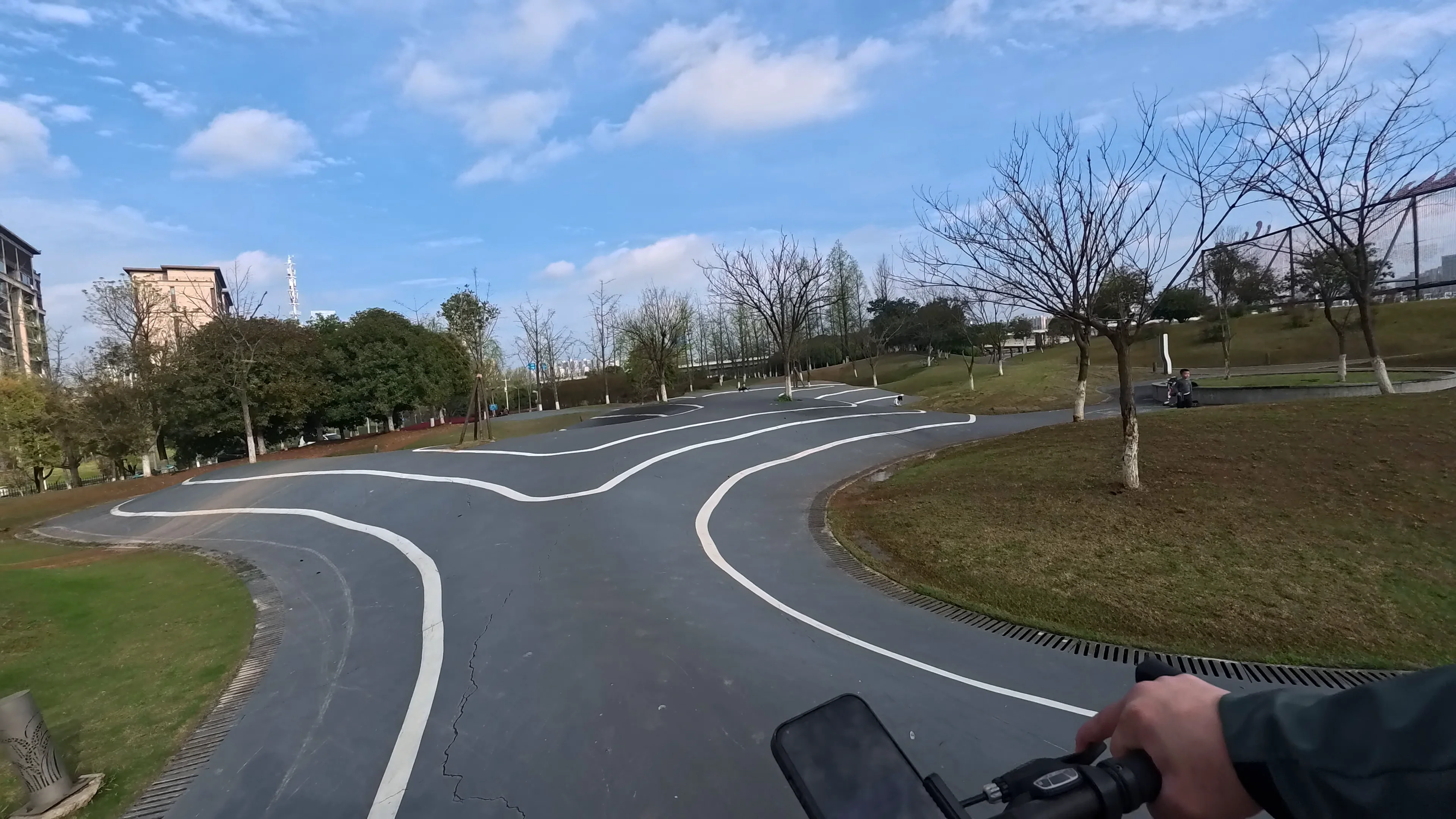 Modern wave-shaped cycling paths inside a quiet urban park in Changsha during a relaxing afternoon ride POV cycling through a flowing modern bike lane inside a peaceful urban park in Changsha, China under a bright blue sky